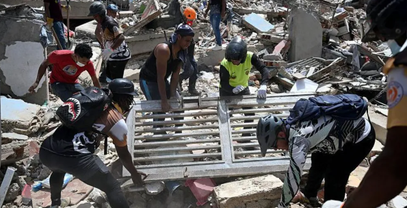 Volunteers lift a metal gate as they search through debris on the rubble of collapsed buildings in Catia La Mar. PHOTO FILE Getty Images